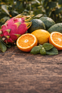 Auswahl frischer Früchte: Pitaya, Avocados und Orangen auf Holzoberfläche