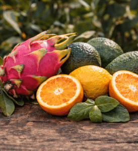 Selección de fruta fresca: pitaya, aguacates y naranjas sobre superficie de madera